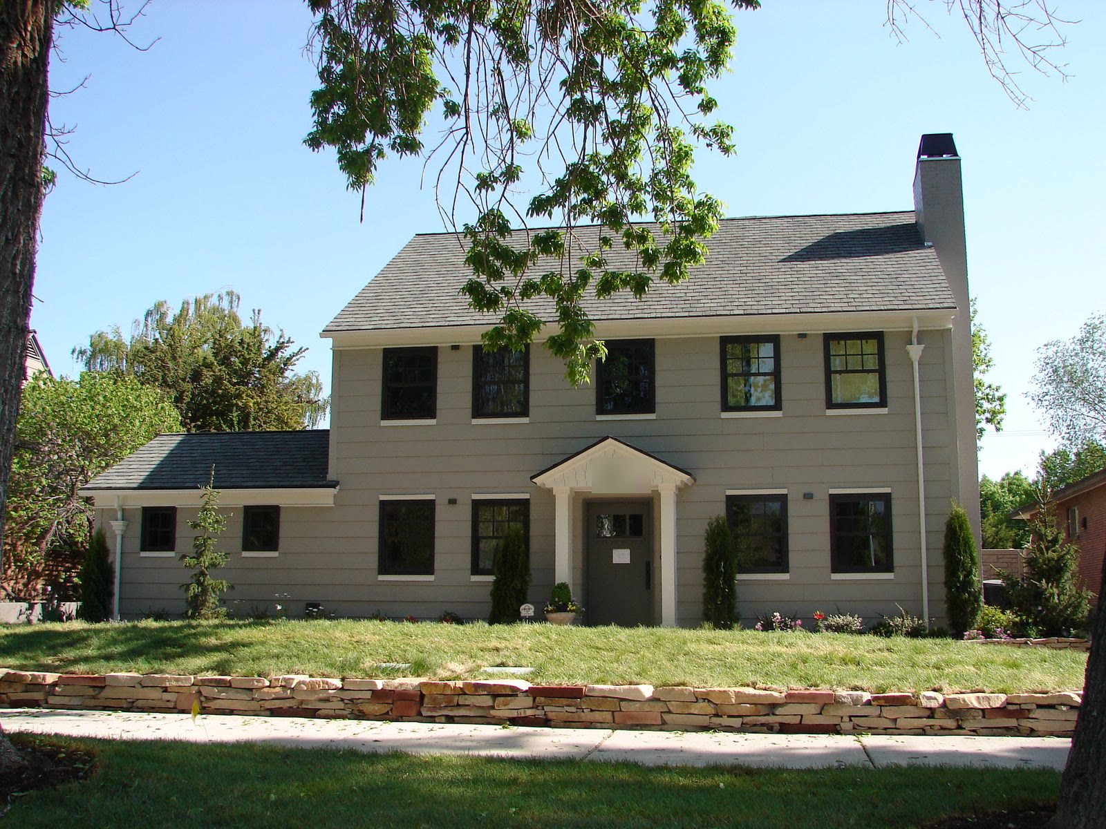 The same home after renovation, grey shingle and lap siding with new windows