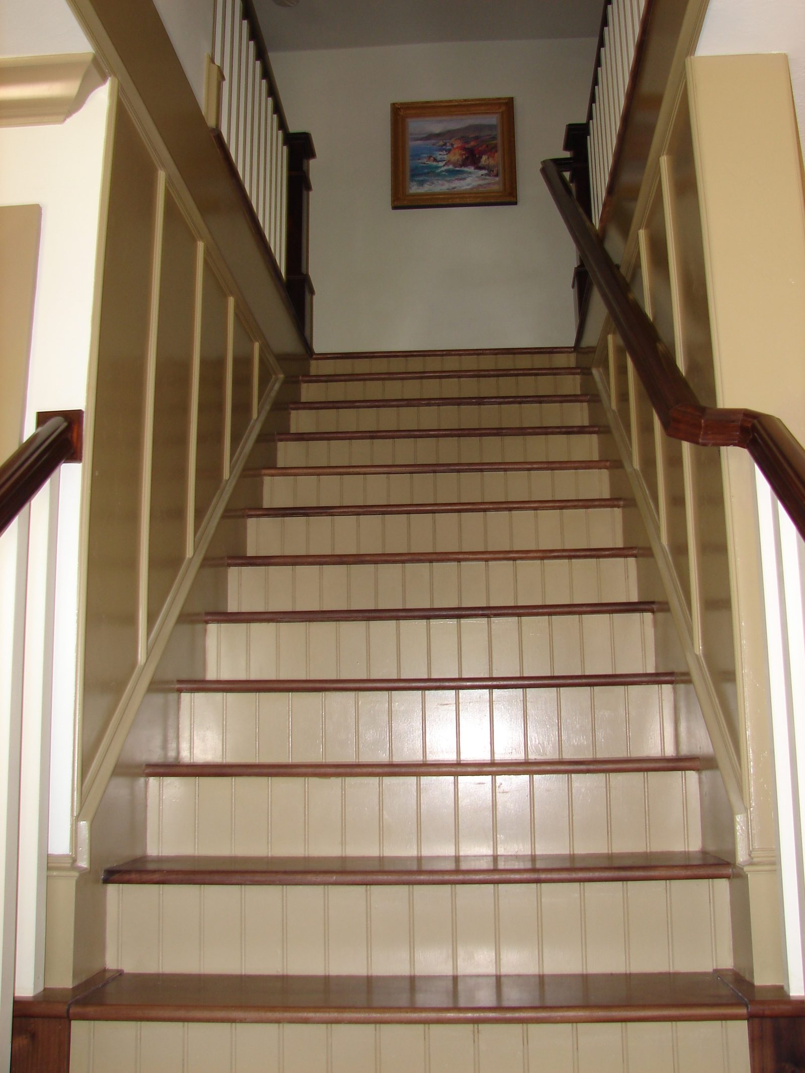 Interior staircase with painted risers and a wood handrail