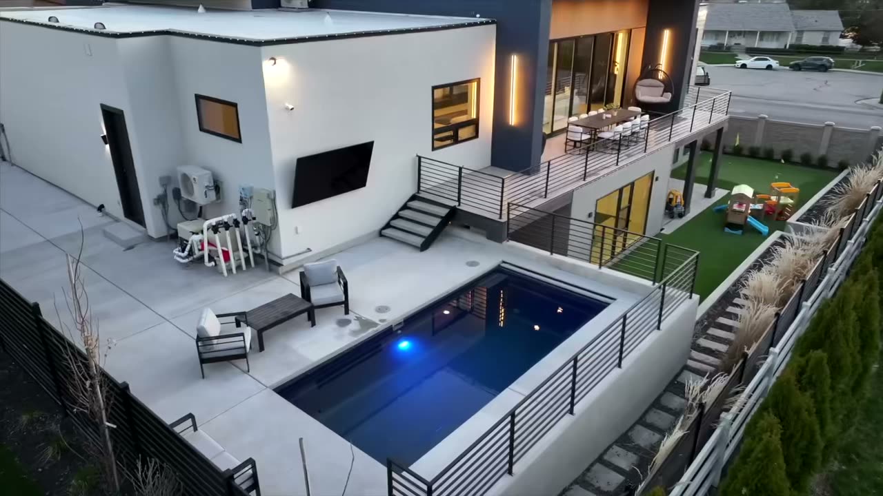 Aerial view of the back of the home with a pool, turf, and a sport court