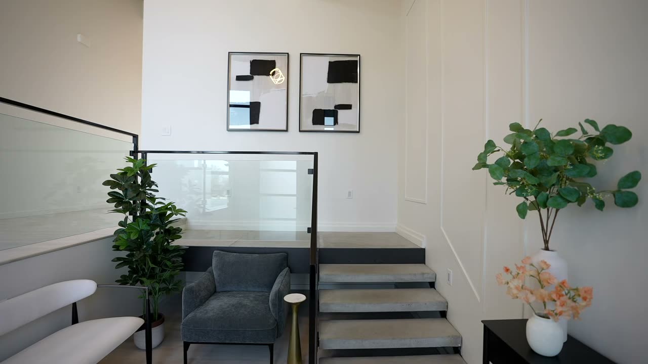 Double-height entry with a floating stair and a glass guardrail