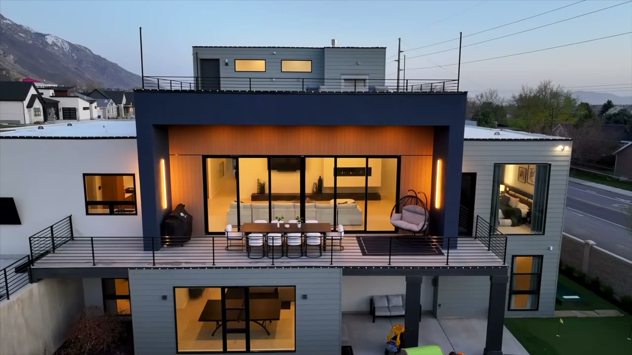 Rear elevation at dusk with the interior lit and a covered upper deck