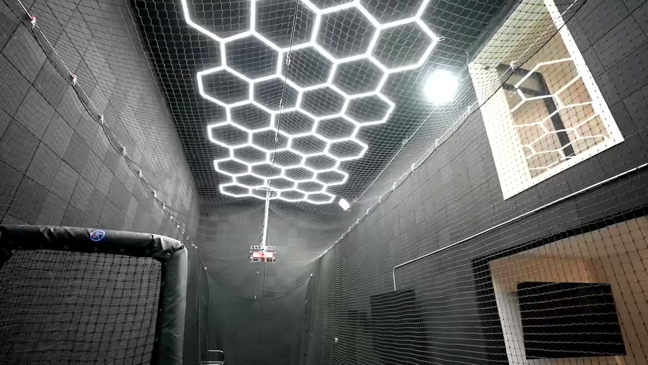 Home gym with hexagon LED ceiling lighting and a netted sport area