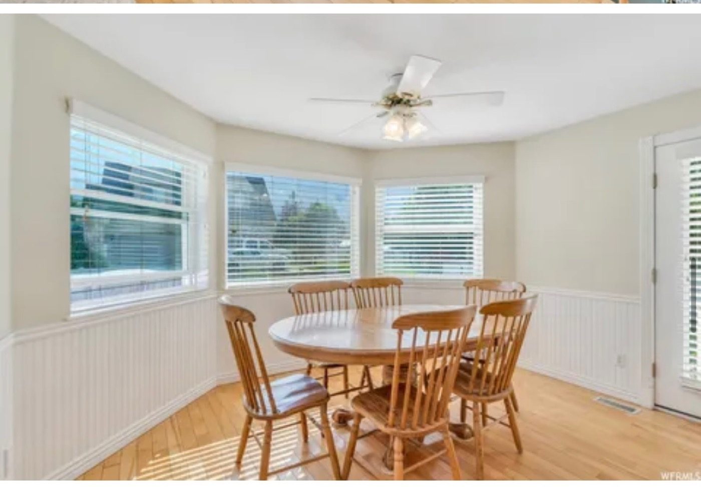 A dining area with oak trim, floral wallpaper, and green carpet before the renovation