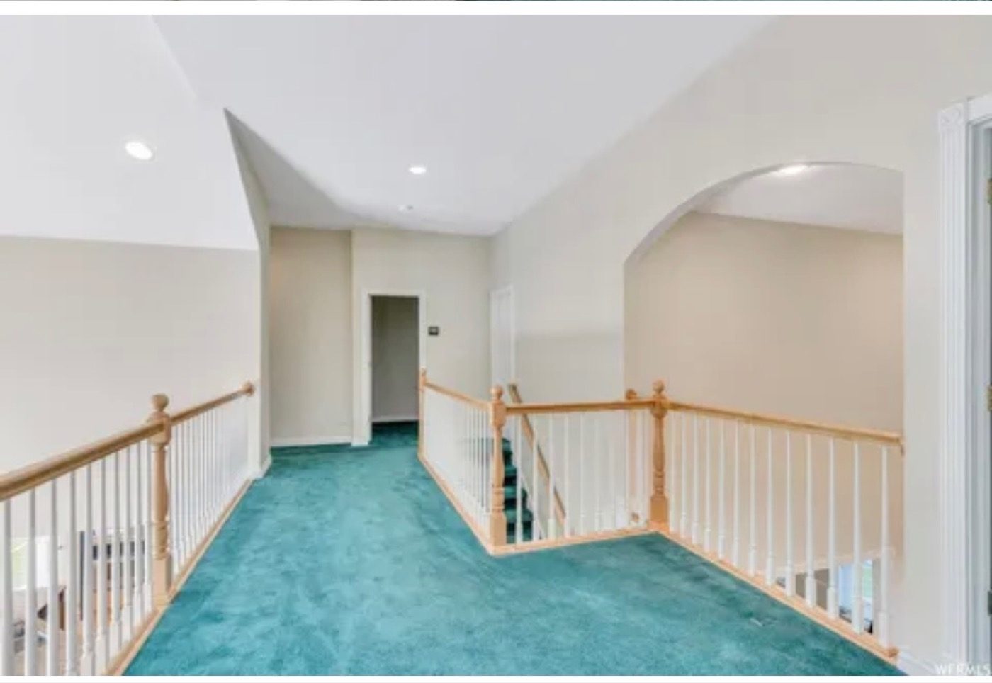 A carpeted loft with a sloped ceiling and green carpet before the renovation