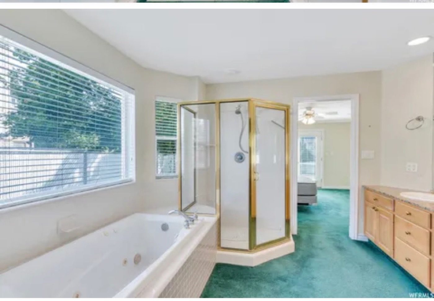 A primary bathroom with an oak vanity and a brass shower before the renovation