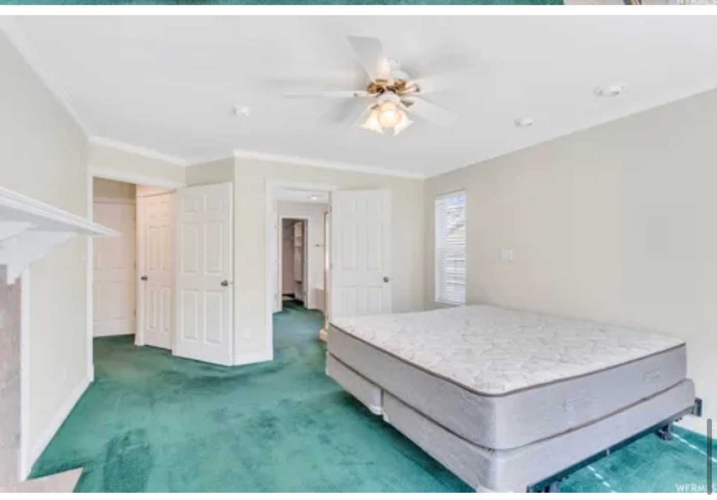 A primary bedroom with green carpet and a mattress on the floor before the renovation