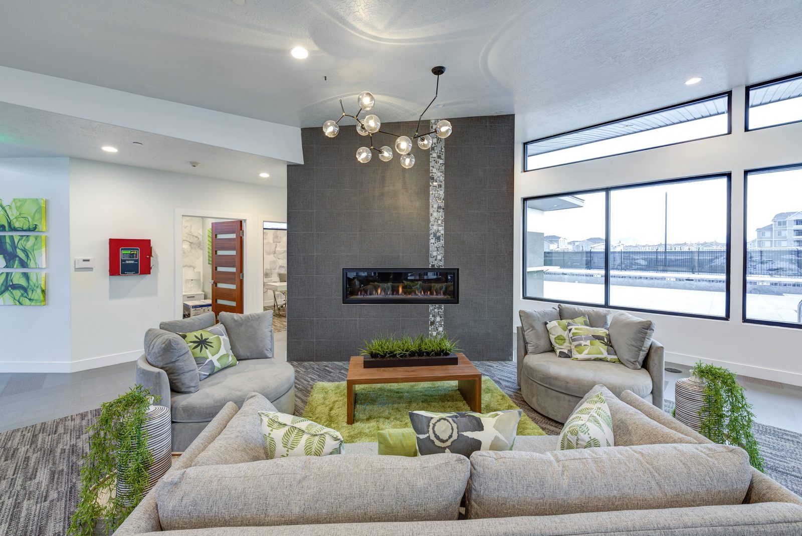 The Vine clubhouse lounge with a linear fireplace, lounge seating, and floor-to-ceiling windows