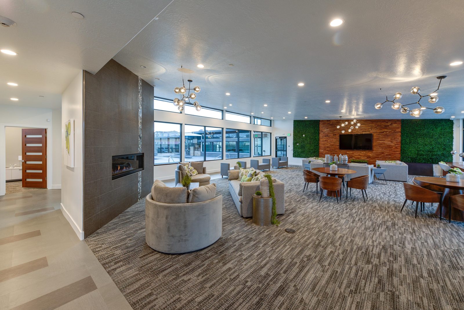 Open clubhouse great room at The Vine with lounge and dining areas and a moss accent wall