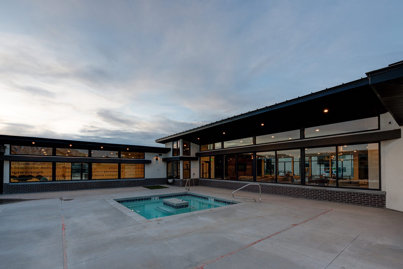 The Vine clubhouse and pool at dusk, a long low amenity building beside a courtyard pool