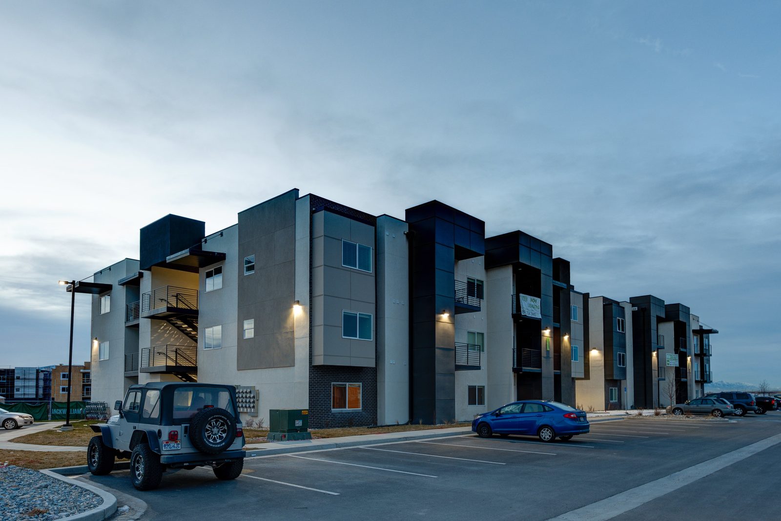 The Vine apartment community in Vineyard at dusk, several modern residential buildings lit against the mountains